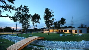 A modern building with a glass facade, surrounded by a well-maintained lawn and a wooden bridge. - Luxury Villa Zio with Pool (Novigrad)