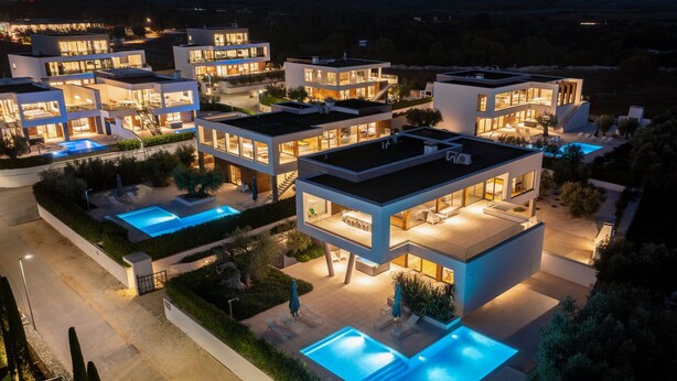Un moderno edificio residencial de varios pisos con múltiples balcones y una piscina.