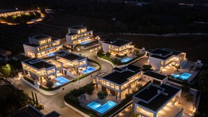 Un complejo residencial moderno con varias casas de dos pisos, cada una con piscina privada y zonas exteriores bien iluminadas.