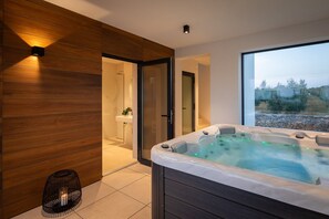 Relax in a spacious bathroom with a glass-enclosed shower and a hot tub, offering a view of the outdoors.
