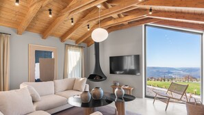 A modern living room with a wooden ceiling, a fireplace, a large window with a view, and a flat-screen TV. - Villa Vista Verde with Pool (Grožnjan)