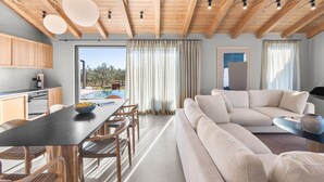 A modern living room with a large sofa, a dining table with chairs, and a kitchen area with wooden cabinets. - Villa Vista Verde with Pool (Grožnjan)