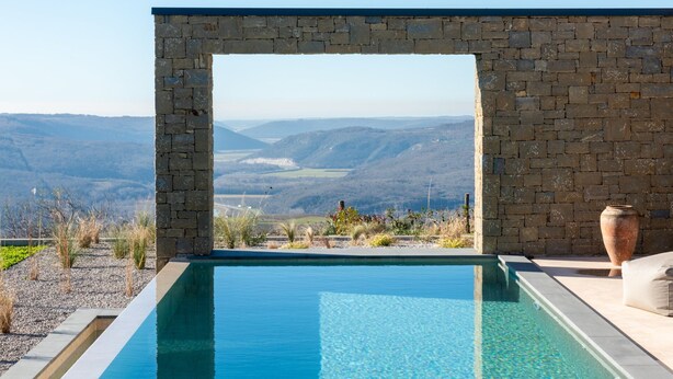 A stone-framed infinity pool with a clear view of distant hills. - Villa Vista Verde with Pool (Grožnjan)