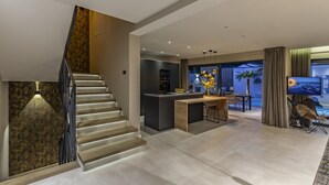 A modern interior with a staircase, a kitchen area, and a dining space. - Luxury Villa Xquisite with Pool (Medulin)