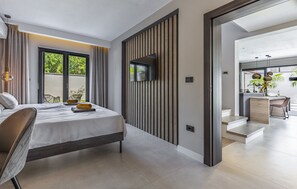 A modern bedroom with a bed, a TV mounted on a wooden panel wall, and a view of the outdoor balcony. - Luxury Villa Xquisite with Pool (Medulin)