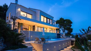 A modern two-story house with a swimming pool, outdoor seating, and a well-lit balcony. - Villa Hestia with Heated Pool (Lumbarda)