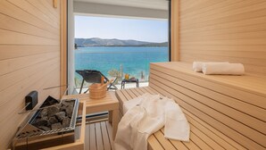 Un sauna avec un banc en bois, une table avec une serviette et une vue sur un lac.