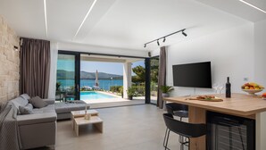 Un salon moderne avec un canapé, une table basse et un coin repas équipé d’une télévision et d’un corbeille de fruits.