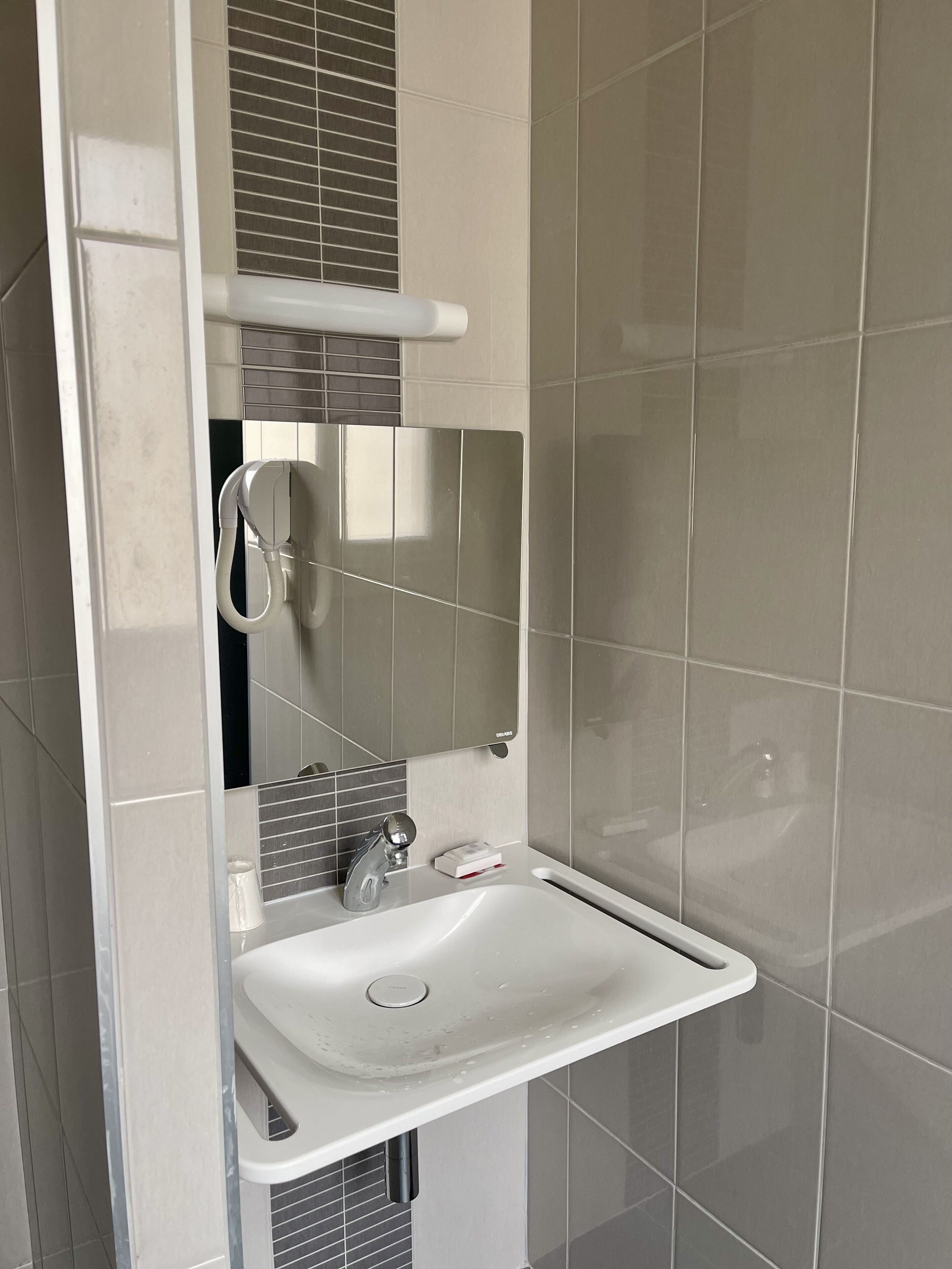A modern bathroom with a white sink, a mirror, and a towel rack.