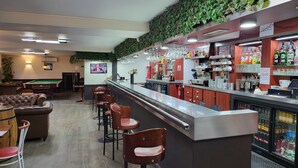 Zona de bar con mesa de billar, taburetes y una pantalla de televisión.