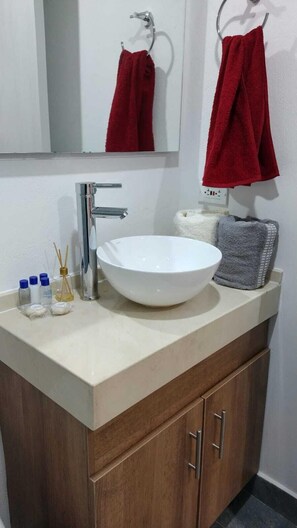 A bathroom with a white sink, a mirror, and a red towel hanging on a towel rack. - Hermoso Apartaestudio en centro Bogotá (Bogotá)