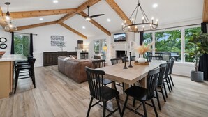 A spacious kitchen with a large island, wooden beams, and a dining area with chairs.