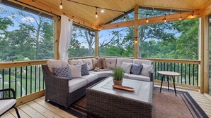 A covered outdoor seating area with a sofa, a coffee table, and a small table.