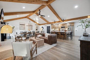 A spacious living area with a high ceiling, wooden beams, a dining area, and a kitchen with modern appliances.