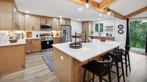 A modern kitchen with wooden cabinets, a central island, and a large window.