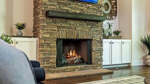 A stone fireplace with a fire, white cabinets, and a rug on the floor. - Mountain Hideaway 8 acres - 5 Bedrooms + Hot Tub (Hendersonville)