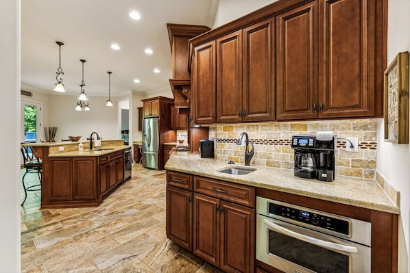 A kitchen with wooden cabinets, a granite countertop, a built-in oven, and a coffee maker.