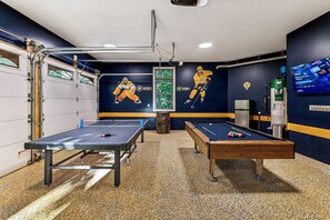 Une salle de billard équipée de deux tables de billard, d’une table de pool et d’une table de baby-foot.