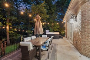 Eine Terrassengruppe mit Holztisch, Korbstühlen und Grill.