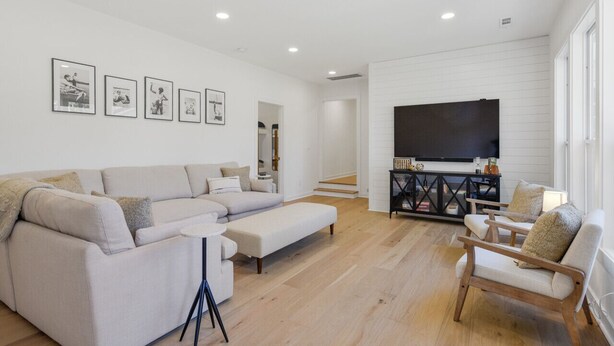 A modern living room with a sectional sofa, a coffee table, and a TV mounted on the wall. - Urban Rustic Lakeside Retreat with Dock, Sleeps 20 (Gallatin)