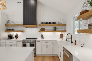 A modern kitchen with white cabinetry, wooden shelves, and a stainless steel stove. - Urban Rustic Lakeside Retreat with Dock, Sleeps 20 (Gallatin)