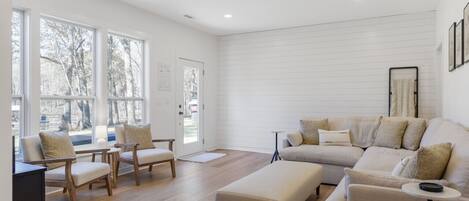 Uma sala de estar moderna com um sofá, cadeiras e uma mesa de centro.
