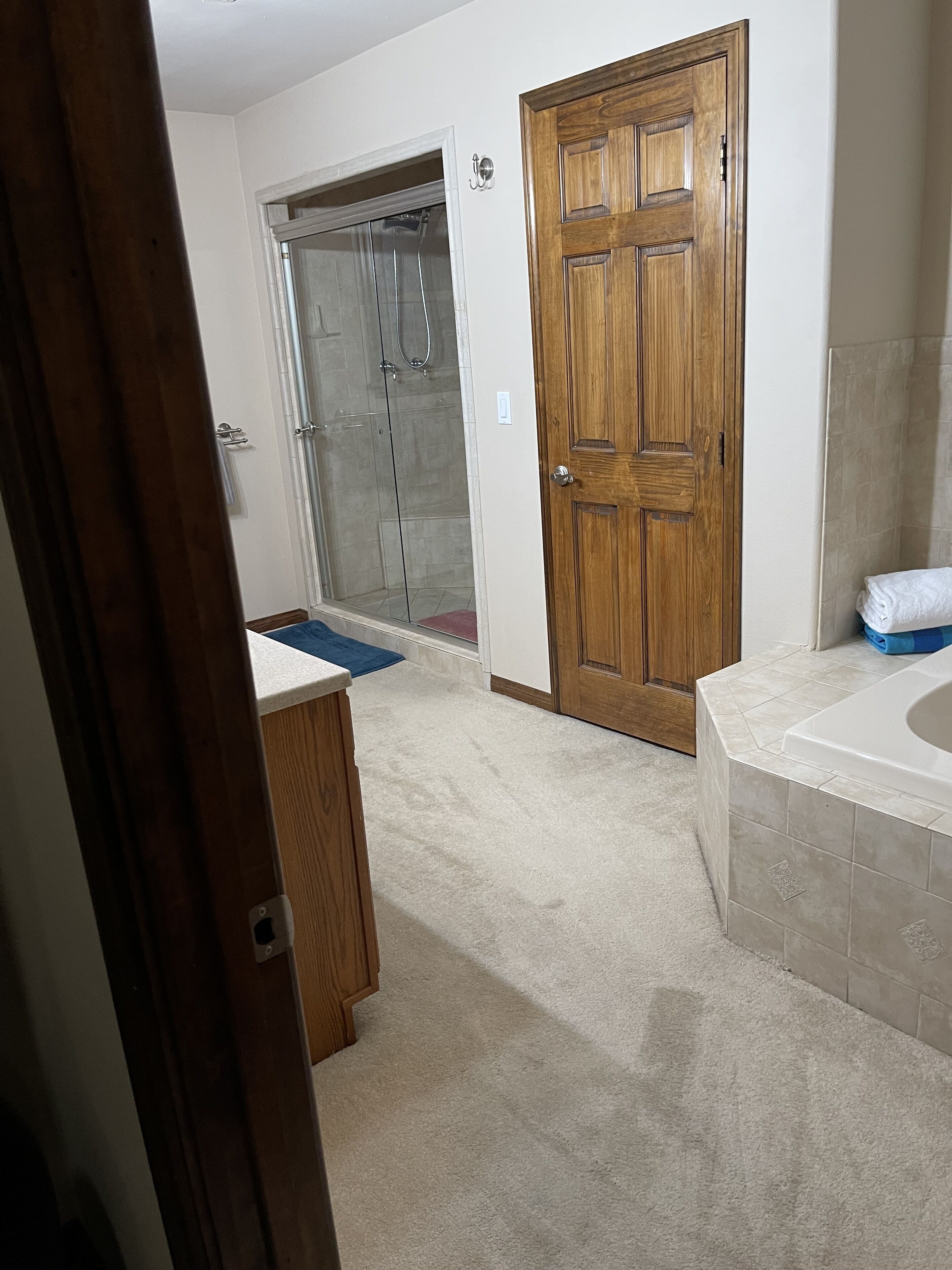 Une salle de bain avec une porte en bois, une douche et une baignoire.