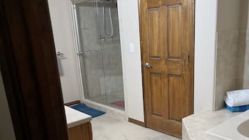 A bathroom with a wooden door, a shower, and a bathtub.