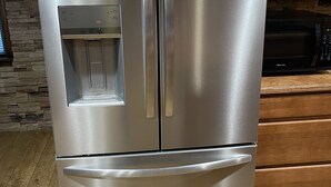 Un refrigerador de acero inoxidable con compartimento congelador, dispensador de agua y hielo, e hacedor de hielo incorporado.
