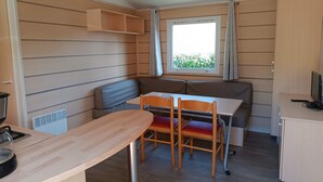 A compact kitchenette with a stove, a sink, and a window with curtains.