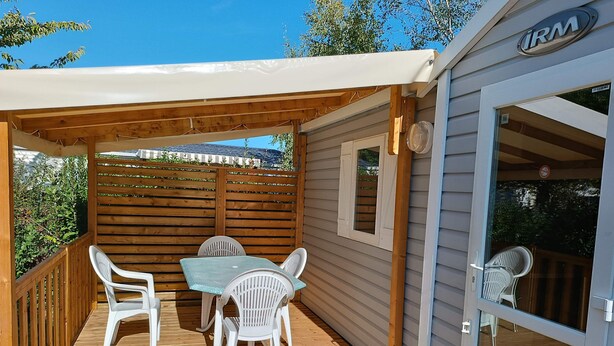 A wooden deck with a table and chairs, a covered area, and a sliding glass door.