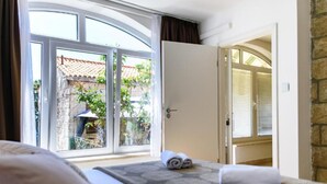 Une chambre d’hôtel avec un lit, une fenêtre donnant sur l’extérieur et une porte menant à une autre pièce.