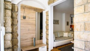 Une pièce moderne avec un mur en pierre, un meuble en bois doté de tiroirs, un panier suspendu et un canapé.
