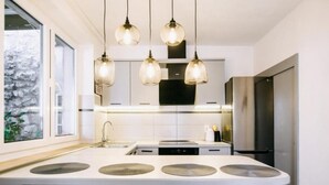 Une cuisine moderne dotée d’un îlot central, de luminaires suspendus et offrant une vue sur un mur en pierre.