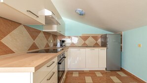 A compact kitchen with a wooden countertop, white cabinets, a stainless steel refrigerator, and a gas stove. - Nova- two bedroom apartment with terrace (Zadar)