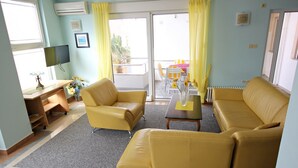 A living room with yellow sofas, a TV, and a table with a vase of flowers. - Nova- two bedroom apartment with terrace (Zadar)