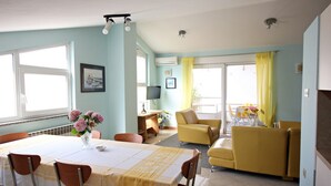 A dining area with a table set for four, a yellow sofa, and a small table with chairs. - Nova- two bedroom apartment with terrace (Zadar)