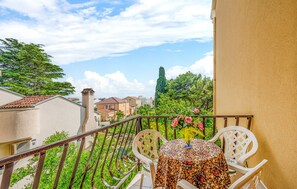 A balcony with a table and chairs, a flower vase, and a view of houses and trees. - Ilaria- Two bedroom apartment with balcony with garden view (Zadar)