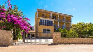 A two-story building with a yellow facade, balconies, and a gated entrance. - Studio apartment with garden view balcony (Zadar)