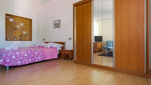 A bedroom with a bed, bedside table, and a wardrobe with a mirror. - Studio apartment with garden view balcony (Zadar)