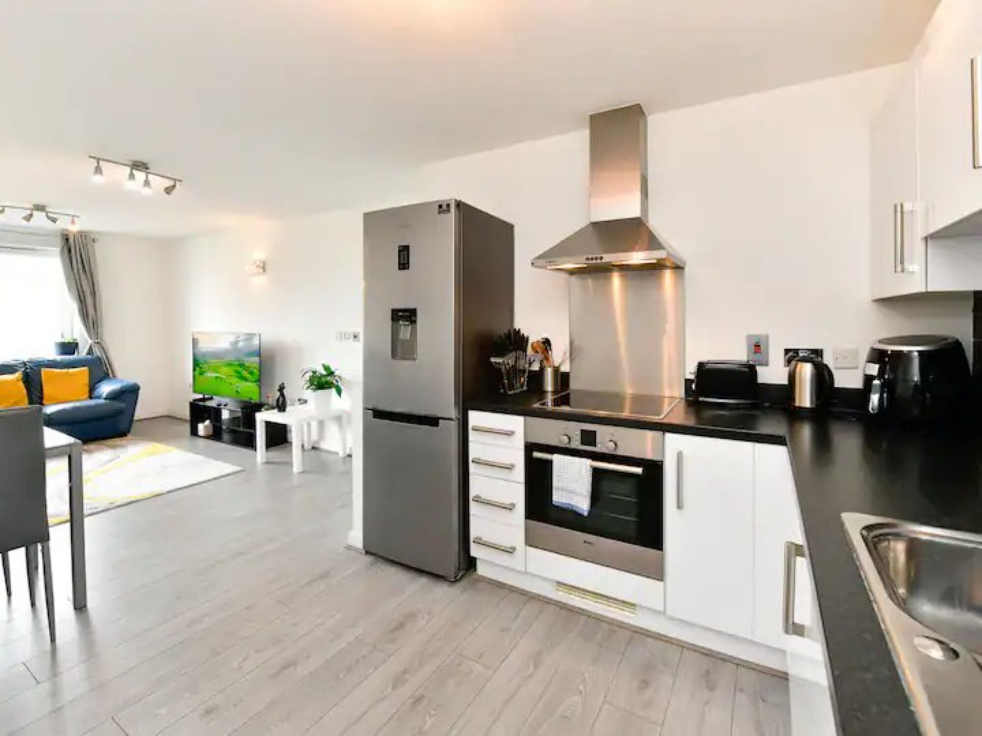 A modern kitchen with a stainless steel refrigerator, oven, and stove, white cabinets, and a black countertop.
