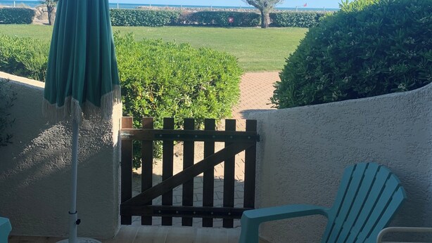 A patio with a view of a grassy field and a wooden fence.