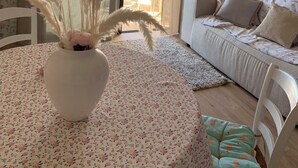 A room with a round table, a white sofa, and a large window with curtains.