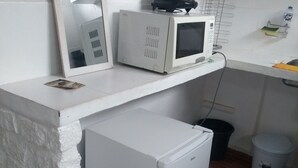 A compact kitchen with a white refrigerator, microwave, and a small sink. - Antonia Hospedaria (Búzios)