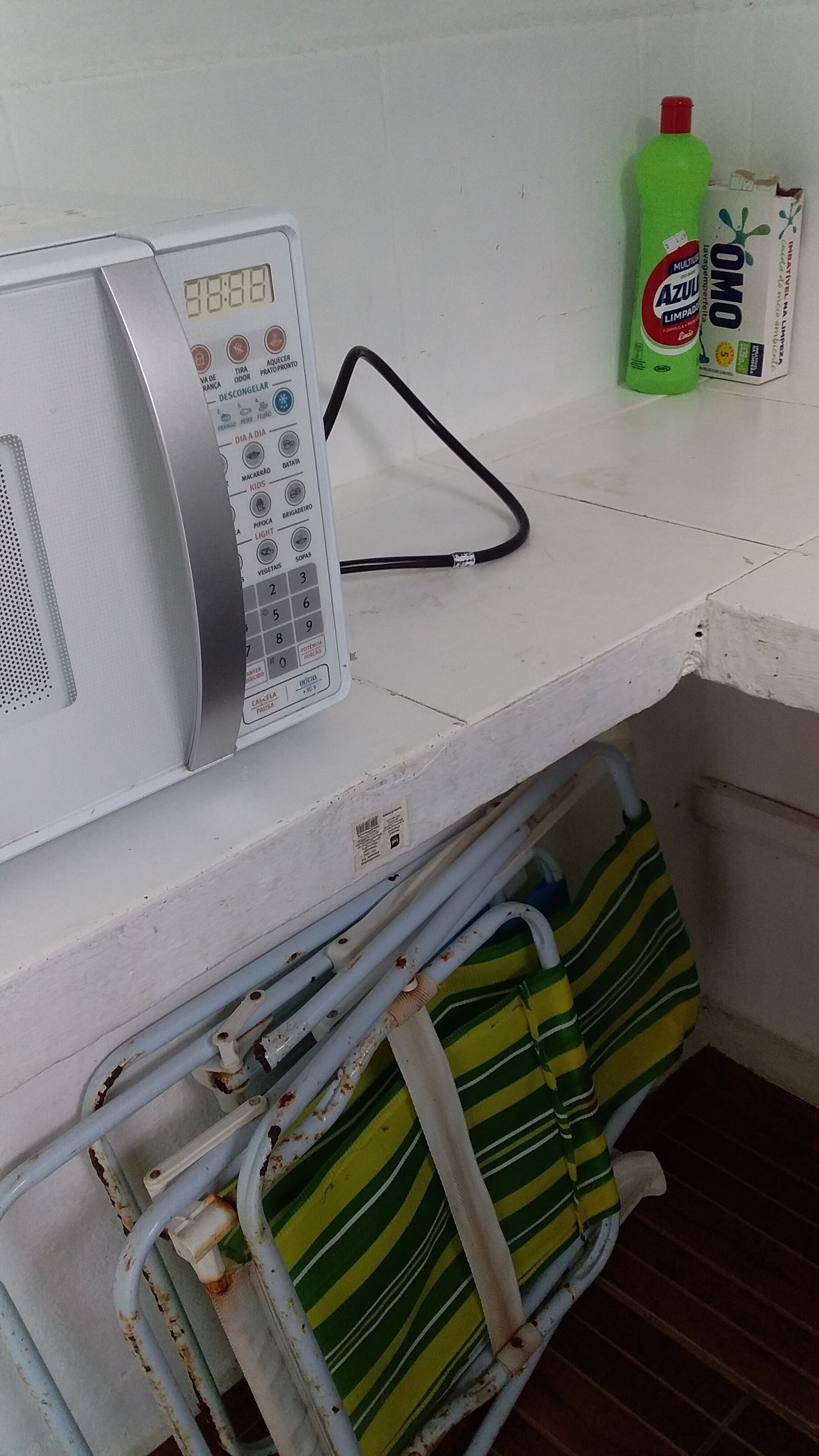 Un microondas, una botella verde y un bolso a rayas en una esquina.