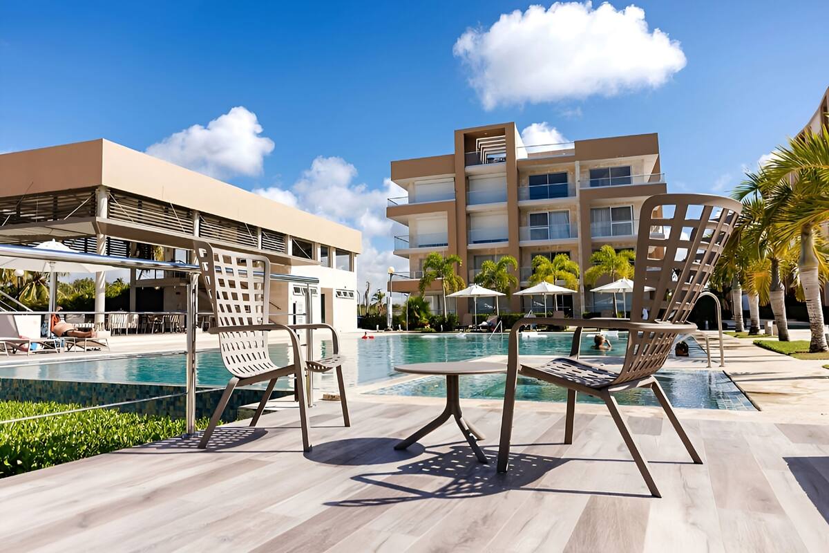 Een modern hotel met een zwembad, terras en een meerlaags gebouw met balkons.