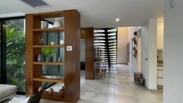Un interno moderno con una libreria in legno al centro, un'area pranzo con una panca e una scala che conduce a un altro livello.