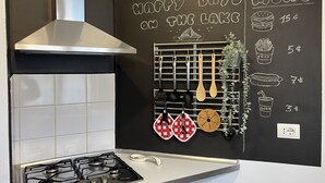 Une cuisine équipée d’une cuisinière à gaz, d’un tableau noir servant de menu et de divers ustensiles accrochés au mur.