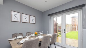 A dining area with a wooden table set for four, grey upholstered chairs, and framed inspirational artwork on the wall.