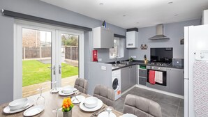A modern kitchen with grey cabinets, a built-in oven, and a dining area with a table set for four.
